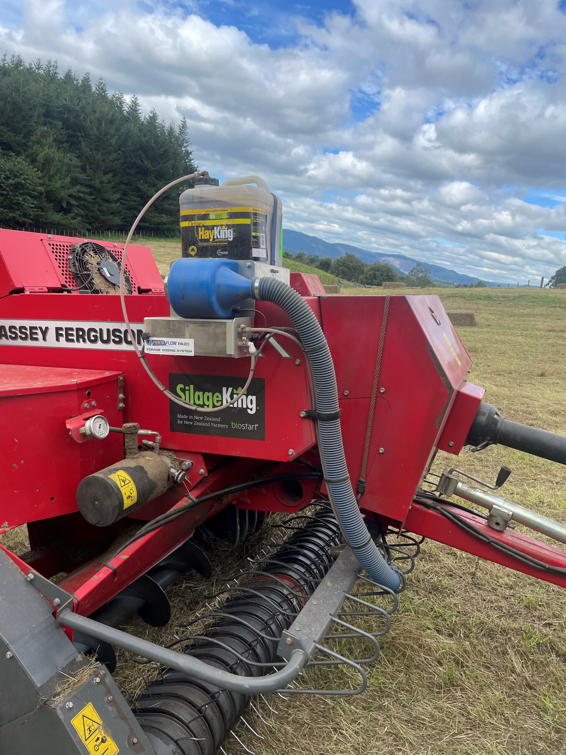 This image shows silage-making machinery with a can of SilageKing connected to it.
