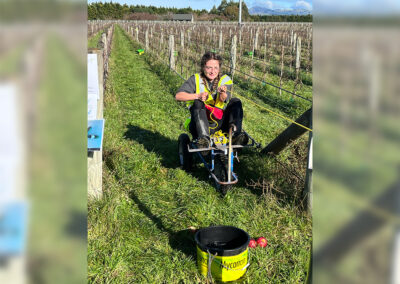 A Hortisports competitor pulls themselves along on a small wheeled vehicle in between vines as a part of a Hortisports challenge.